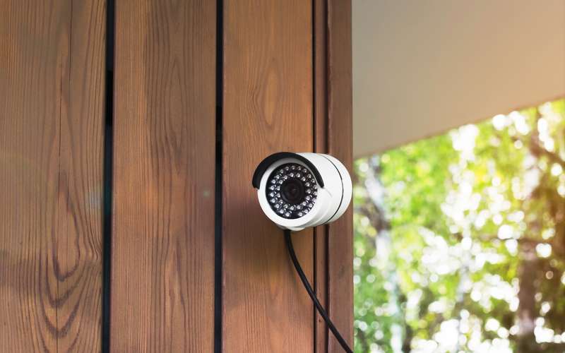 A security camera on the wall of a wooden house