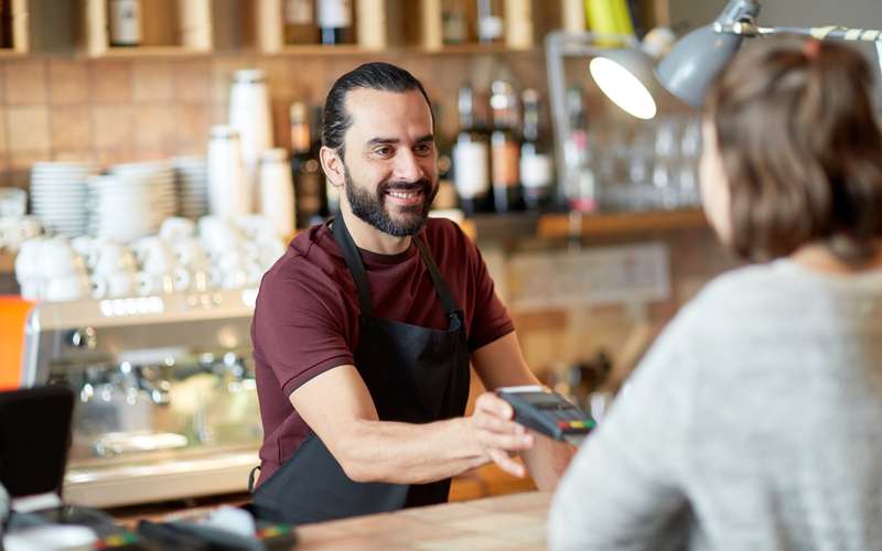 A small-business counter where a customer pays with a card reader