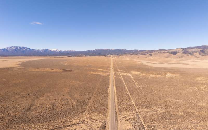 Aerial view of a straight desert road across a Great Basin valley toward snowy peaks