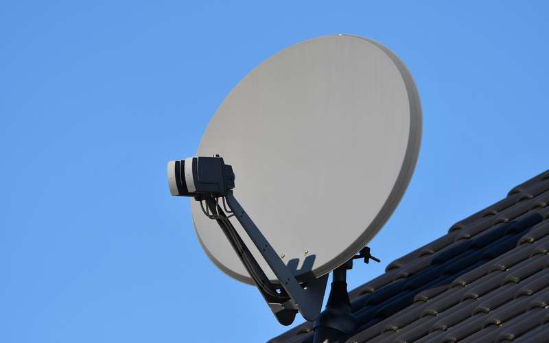 A satellite dish on a tiled roof against a blue sky