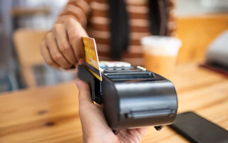A customer tapping a card on a card reader at a counter