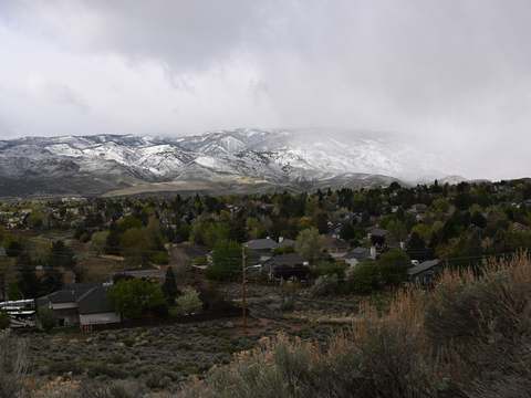 A Reno neighborhood under snow-capped mountains and low clouds, April 2026